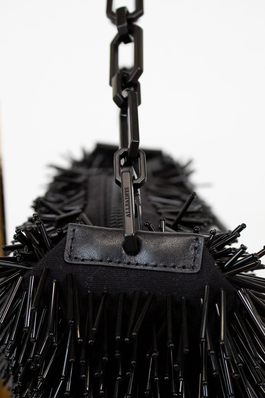 Black spiked handbag with a chain detail on a white background