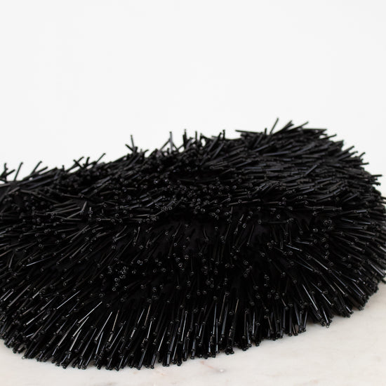 Black beaded purse on a white marble surface