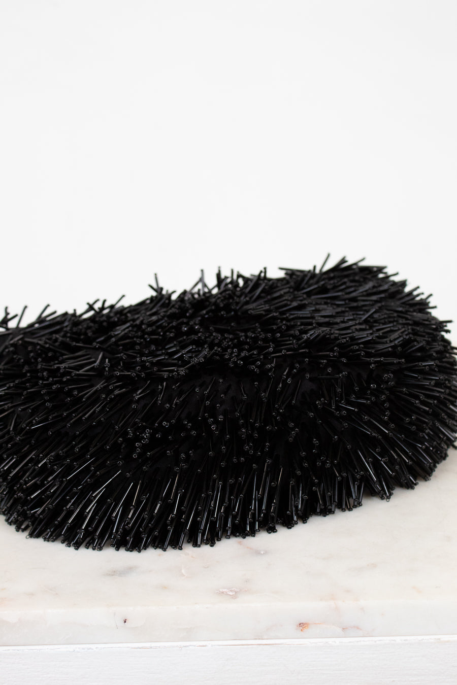 Black beaded purse on a white marble surface