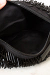 Black fringe clutch bag held open to show interior.