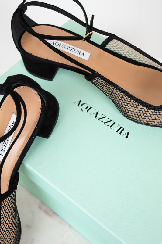 Black Aquazzura shoes on a light green box with visible brand name.
