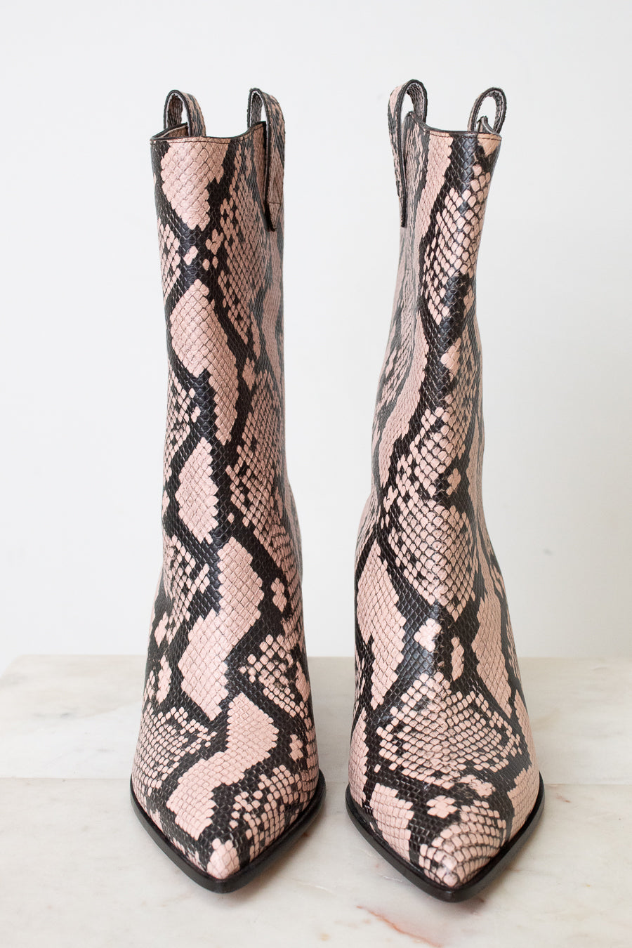 A pair of pointed-toe ankle boots featuring a pink and black snakeskin pattern, displayed against a clean white background.