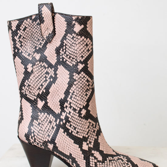 A mid-calf western-style boot with a pink and black snakeskin pattern, featuring a dark brown block heel and pointed toe, set against a plain white background.