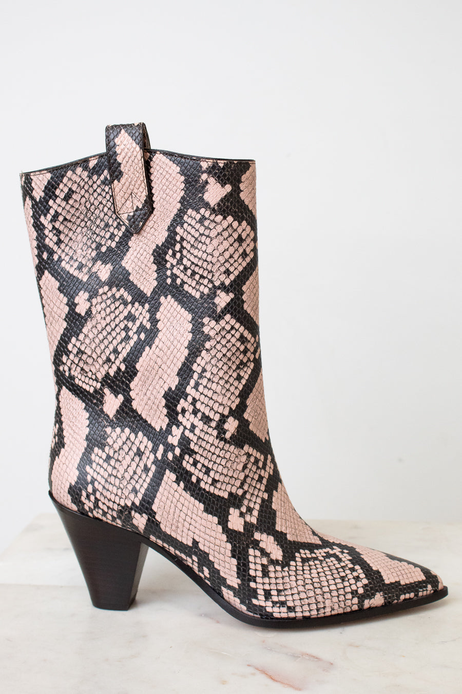 A mid-calf western-style boot with a pink and black snakeskin pattern, featuring a dark brown block heel and pointed toe, set against a plain white background.