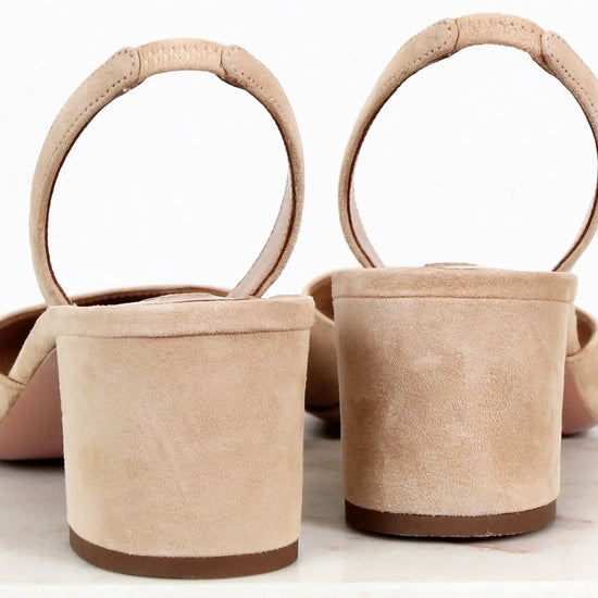 Pair of beige suede shoes with circular handles on a white background