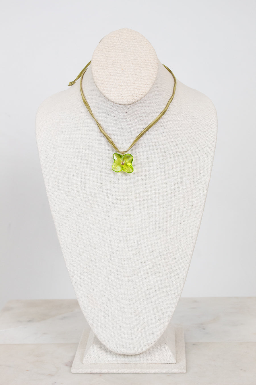 Choker necklace with a green pendant on a mannequin bust against a white background