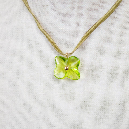 Necklace with a green flower pendant on a light gray background