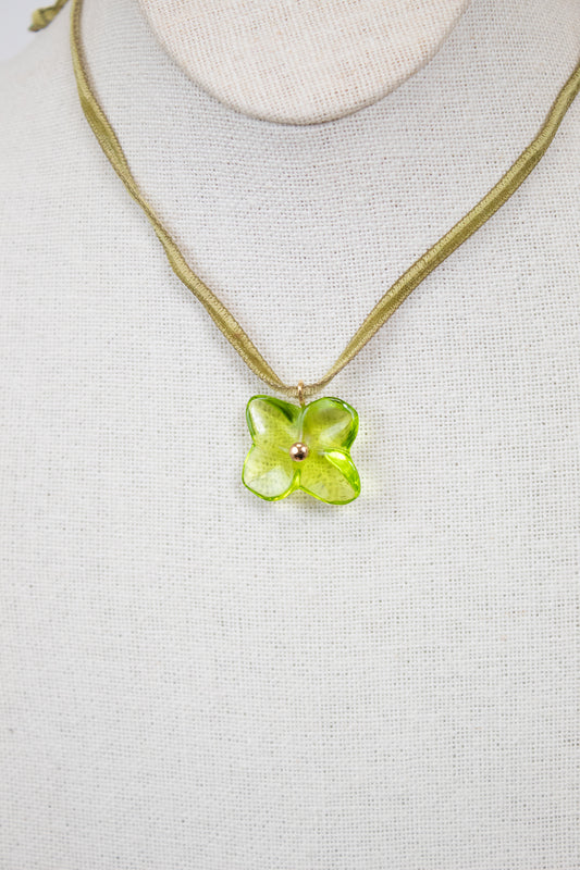 Necklace with a green flower pendant on a light gray background