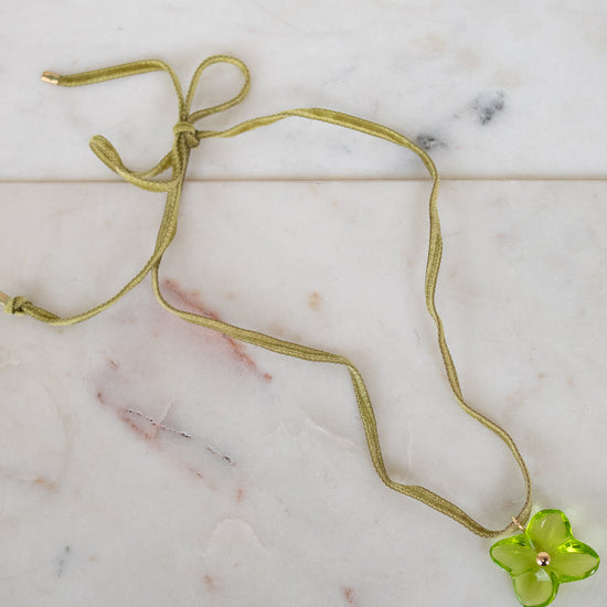 Green necklace with a green flower pendant on a marble surface