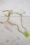 Green necklace with a green flower pendant on a marble surface
