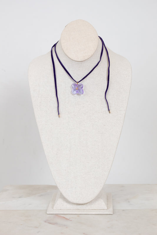 Necklace with a purple flower pendant on a mannequin bust against a white background