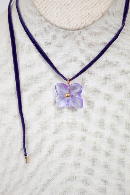 Necklace with a purple flower pendant on a mannequin.