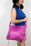 Woman holding a pink handbag against a plain background