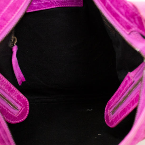 Close-up of a pink handbag with a black interior on a light background