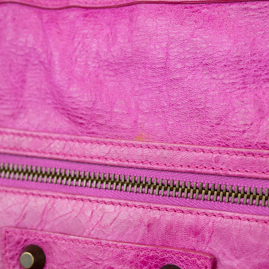 Close-up of a pink textured handbag with a zipper and metal accents.