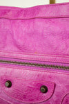 Close-up of a pink textured handbag with a zipper and metal accents.
