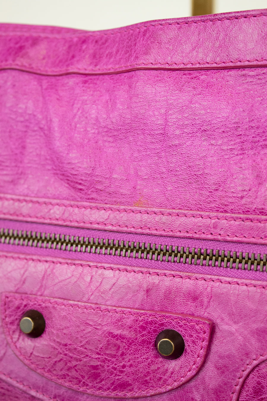 Close-up of a pink textured handbag with a zipper and metal accents.