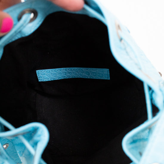 Close-up of a light blue interior of handbag with a hand holding it open, showing the interior.