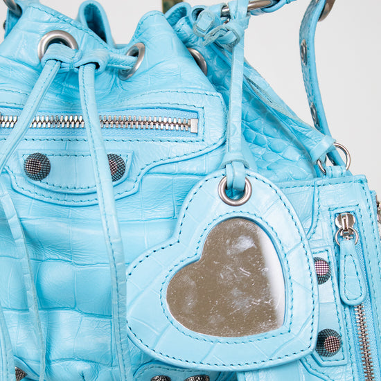 Light blue quilted handbag with heart-shaped pocket on a light background