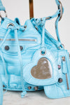Light blue quilted handbag with heart-shaped pocket on a light background