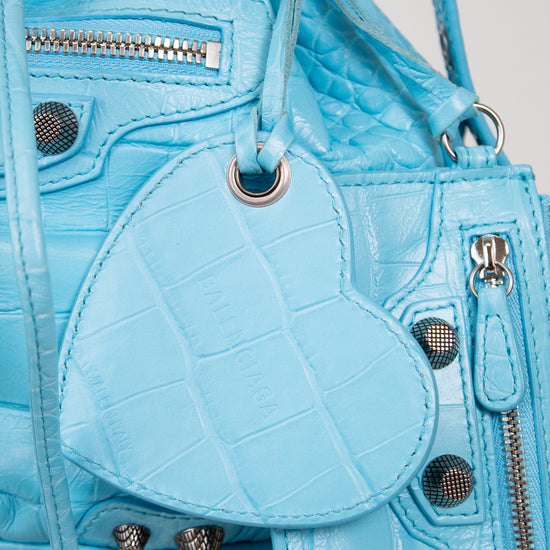 Light blue textured handbag with heart-shaped pouch on a light gray background