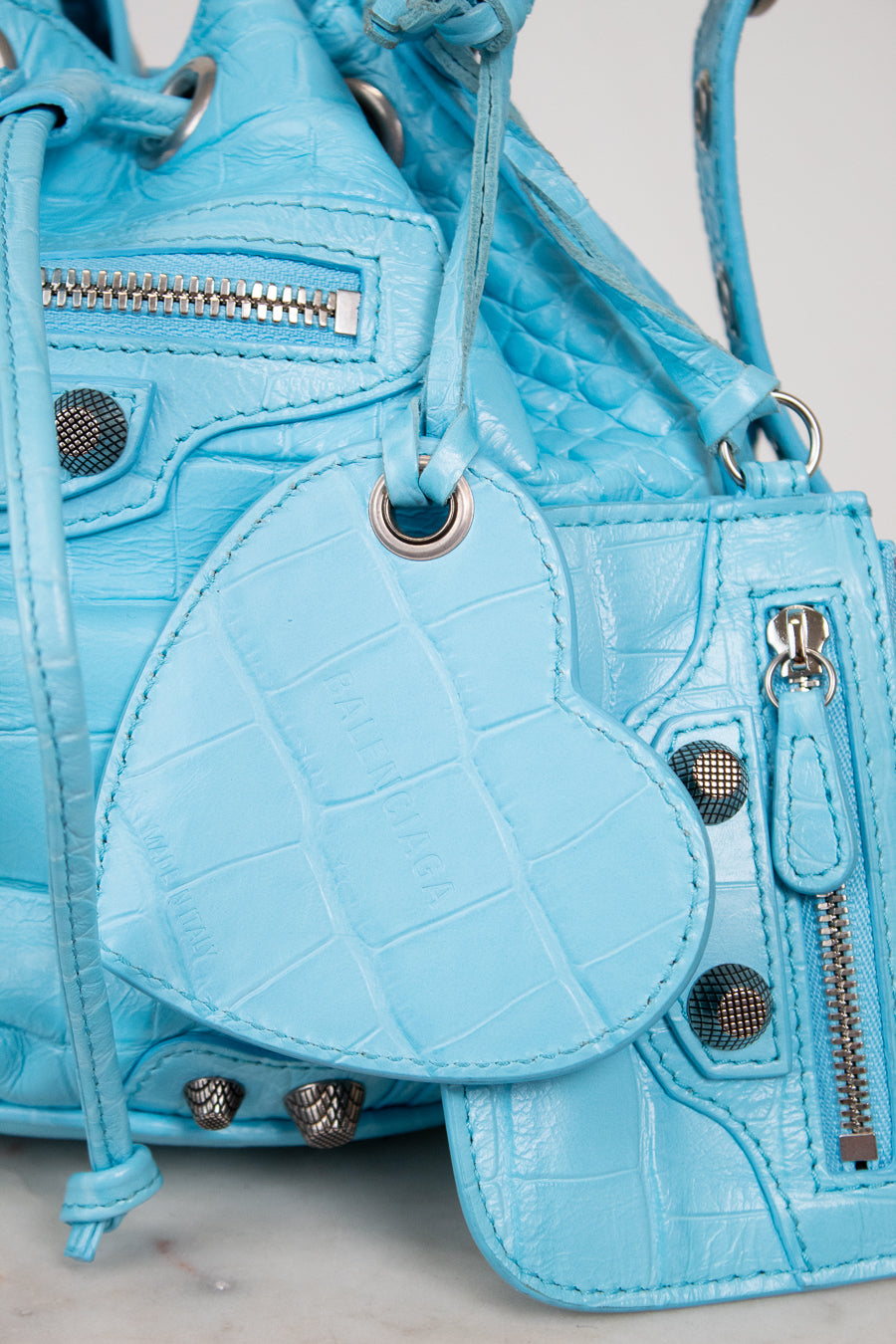 Light blue textured handbag with heart-shaped pouch on a light gray background