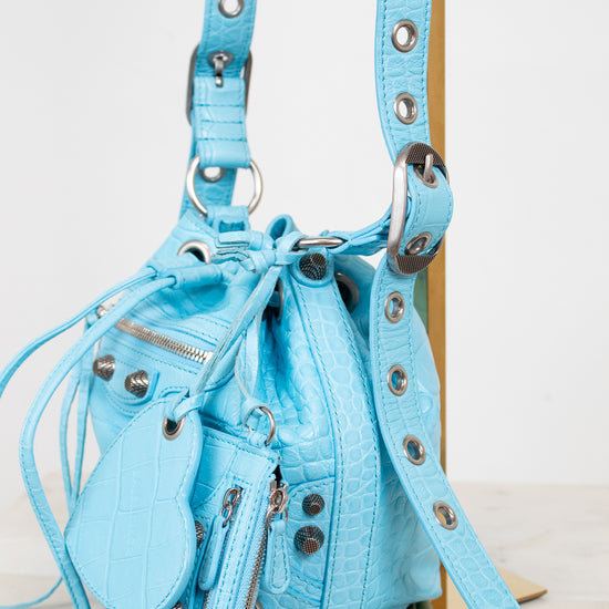 Light blue handbag with studded details on a white background