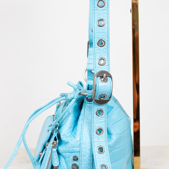 Light blue handbag with decorative straps on a white background