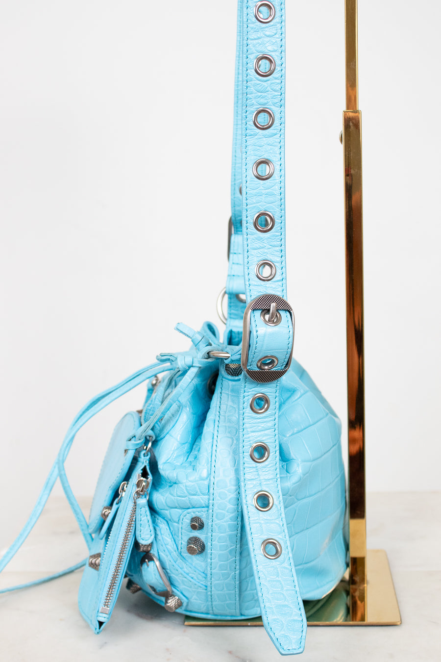 Light blue handbag with decorative straps on a white background
