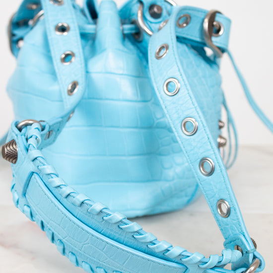 Light blue bucket bag with studded details on a light background