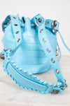 Light blue bucket bag with studded details on a light background