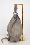 Gray shoulder bag on a gold stand against a white background