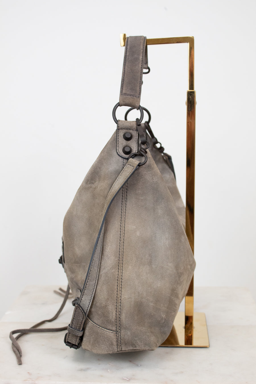 Gray shoulder bag on a gold stand against a white background