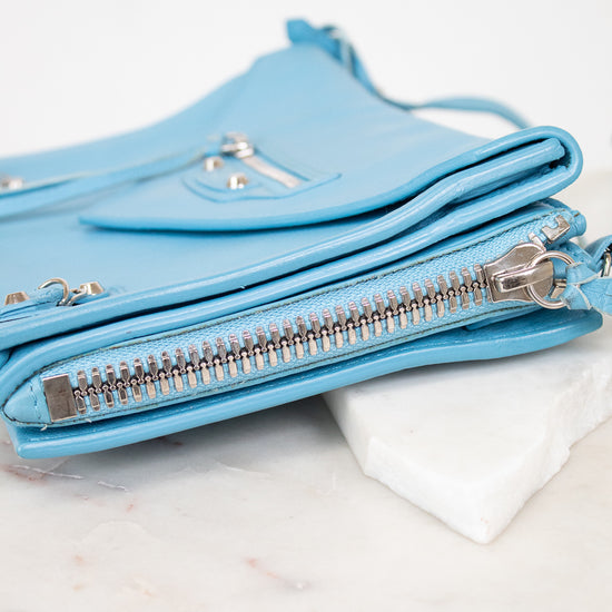 Light blue handbag with zippers on a marble surface