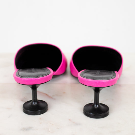 Pair of pink and black high heeled shoes on a marble surface with a white background