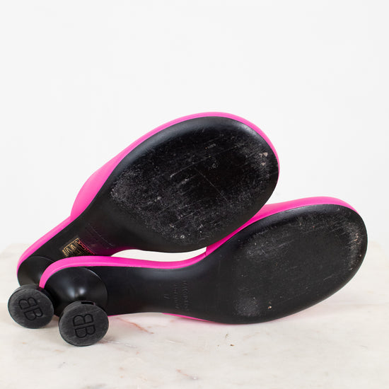 Black and pink high heeled shoe with black sole sitting on a white surface