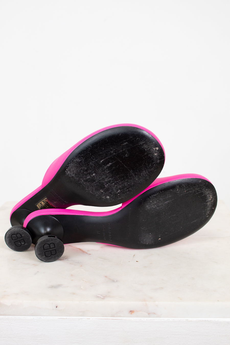 Black and pink high heeled shoe with black sole sitting on a white surface