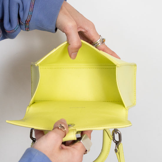Person holding a bright yellow handbag against a plain background
