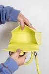 Person holding a bright yellow handbag against a plain background
