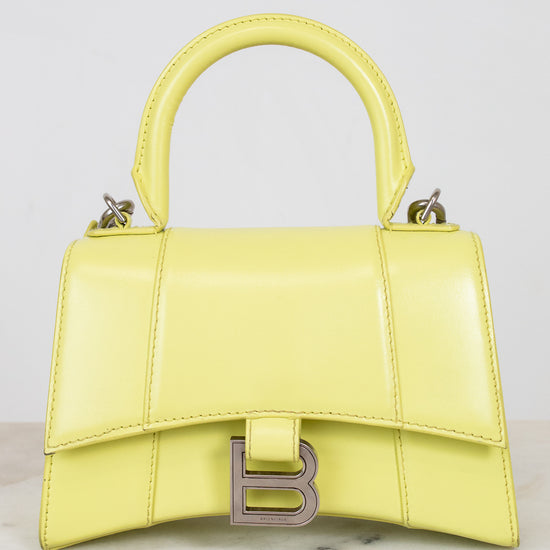 Yellow handbag with a brand logo on a light gray background