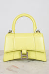 Yellow handbag with a brand logo on a light gray background