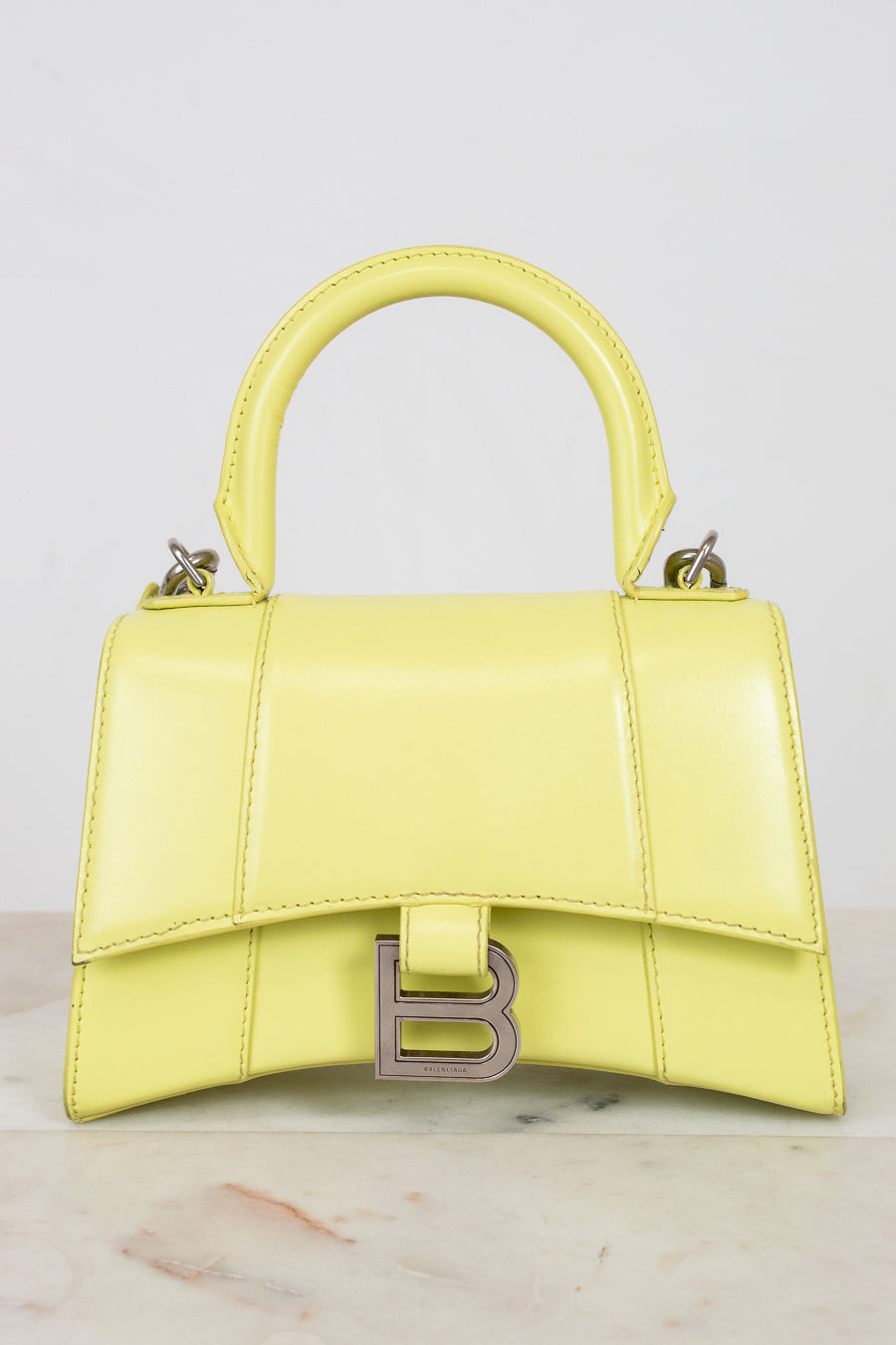 Yellow handbag with a brand logo on a light gray background