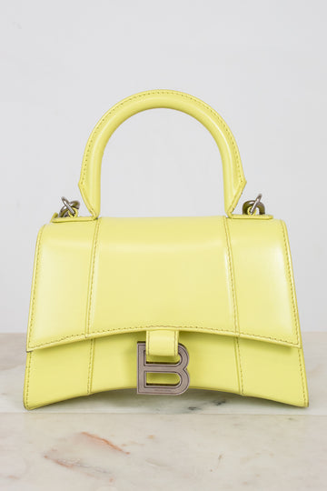Yellow handbag with a brand logo on a light gray background