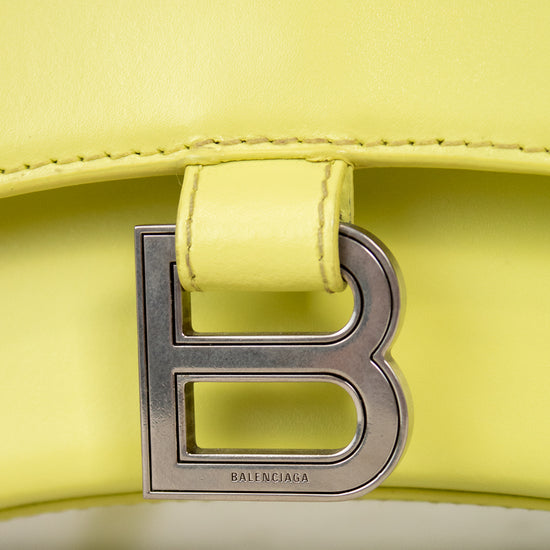 Close-up of a yellow handbag with a silver 'B' logo on a light background