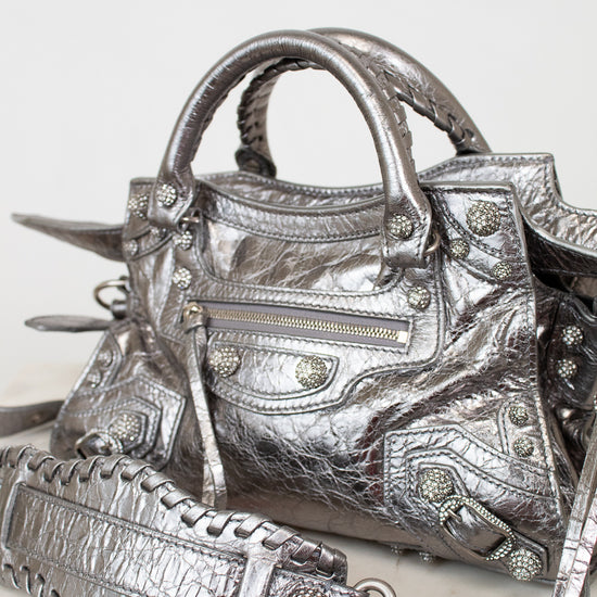 Silver metallic crinkled texture handbag with detailed rhinestone accents on a light background