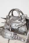 Silver metallic crinkled texture handbag with detailed rhinestone accents on a light background