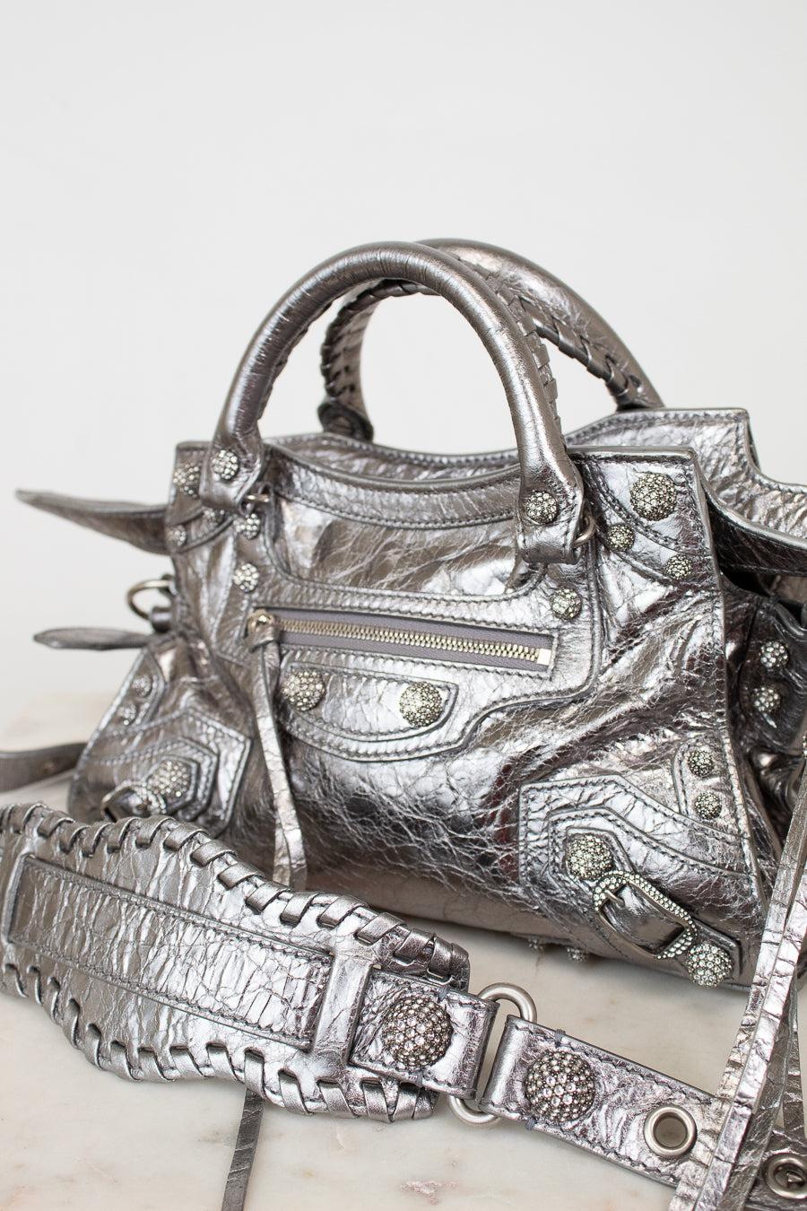 Silver metallic crinkled texture handbag with detailed rhinestone accents on a light background