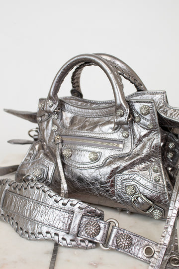 Silver metallic crinkled texture handbag with detailed rhinestone accents on a light background