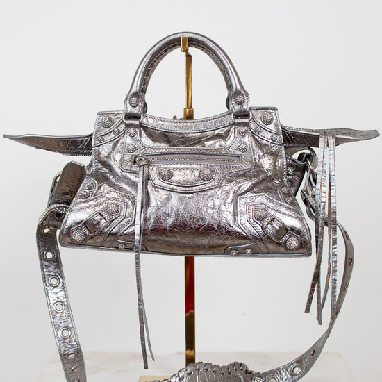 Silver handbag with intricate designs on a white background