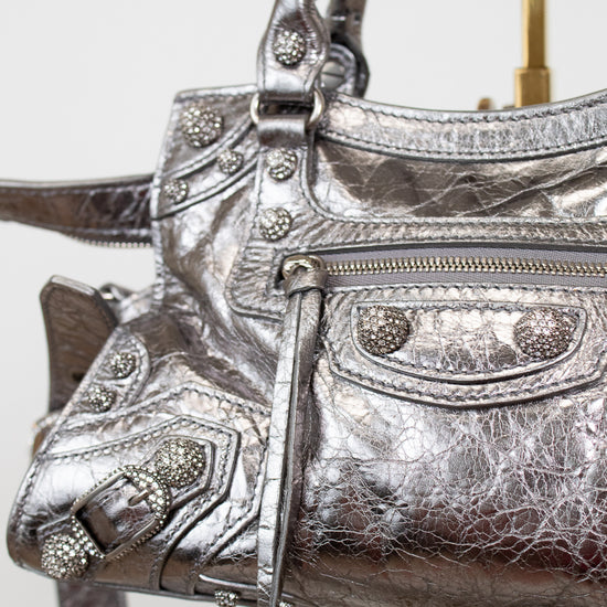 Close up of silver metallic handbag with decorative elements on a white background